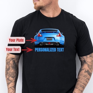 May include: Black t-shirt featuring a blue sports car graphic on the front. The car has a personalized license plate and the words "PERSONALIZED TEXT" below it. The design is a digital illustration.