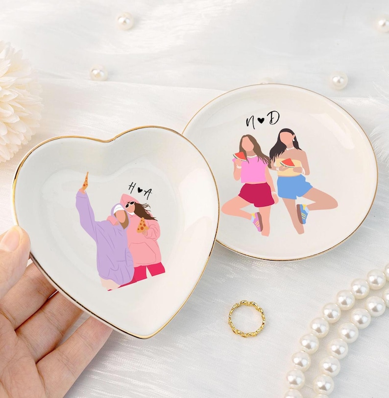 Pu&ograve; includere: Due portagioie decorativi in ceramica. Uno &egrave; a forma di cuore, l'altro rotondo. Entrambi hanno un bordo dorato e presentano illustrazioni di persone. Il piatto a forma di cuore ha le lettere "H&bull;A". Il piatto rotondo ha le lettere "N&bull;D".