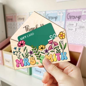 May include: Wooden envelope with a gift card inside. The envelope is decorated with colorful flowers and the text "Thank You Mrs. Smith".