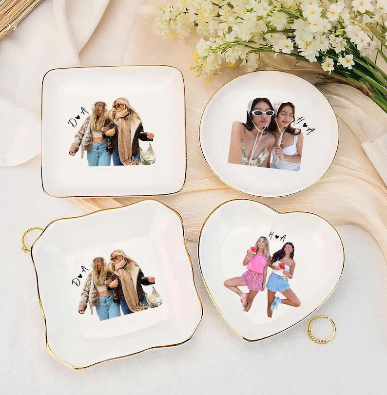 Pu&ograve; includere: Quattro piattini in ceramica bianca con bordi dorati. Ogni piatto presenta una foto diversa di due persone. I piatti sono quadrati, rotondi e a forma di cuore. Un anello d'oro si trova vicino al piatto a forma di cuore. I piatti sono su una superficie bianca.