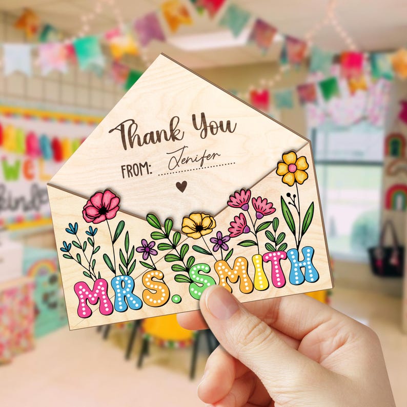May include: Wooden thank you card with a floral design and the text "Thank You" and "From:" with a space for a name. The card is shaped like an envelope and has the name "MRS. SMITH" in colorful letters.