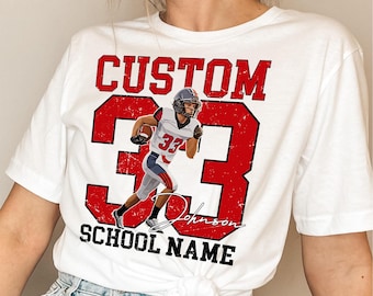 May include: White t-shirt featuring a football player graphic with the number 33 in red. The shirt includes the word "CUSTOM" above the number and "SCHOOL NAME" below. The player is wearing a helmet and holding a football.