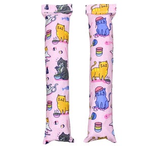 May include: Two pink cat-themed catnip toys with a variety of cats eating ramen and sushi. The toys are made of fabric and have a long, cylindrical shape.