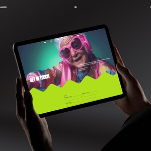 May include: A tablet displays a website with a vibrant design. The screen features an older person wearing pink sunglasses and headphones. The words "GET IN TOUCH" are visible, along with a green wave graphic and form fields. The tablet is held against a dark background.