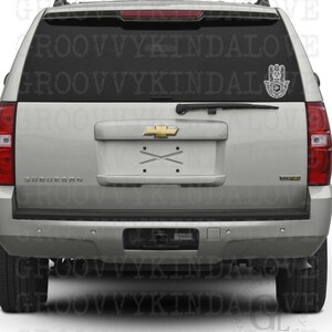 Puede incluir: Un SUV plateado con una calcoman&iacute;a de mano de Hamsa negra en la ventana trasera. La calcoman&iacute;a es un dise&ntilde;o detallado con patrones intrincados. El texto "GROOVY KINDALOVE" es visible en la ventana.