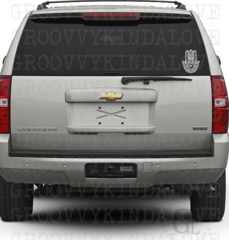 Puede incluir: Un SUV plateado con una calcoman&iacute;a de mano de Hamsa negra en la ventana trasera. La calcoman&iacute;a es un dise&ntilde;o detallado con patrones intrincados. El texto "GROOVY KINDALOVE" es visible en la ventana.