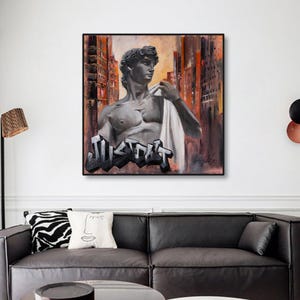 May include: A square canvas wall art piece featuring a greyscale depiction of the statue of David wearing a white earbud. The background shows an abstract orange and brown cityscape. The word JUST DO IT is written in bold black graffiti lettering.