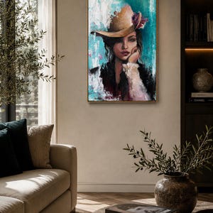 May include: A rectangular framed wall art piece featuring an oil painting of a person wearing a tan hat with a floral accent. The portrait is set against a textured background of vibrant turquoise, white, and black paint strokes with visible brushwork.