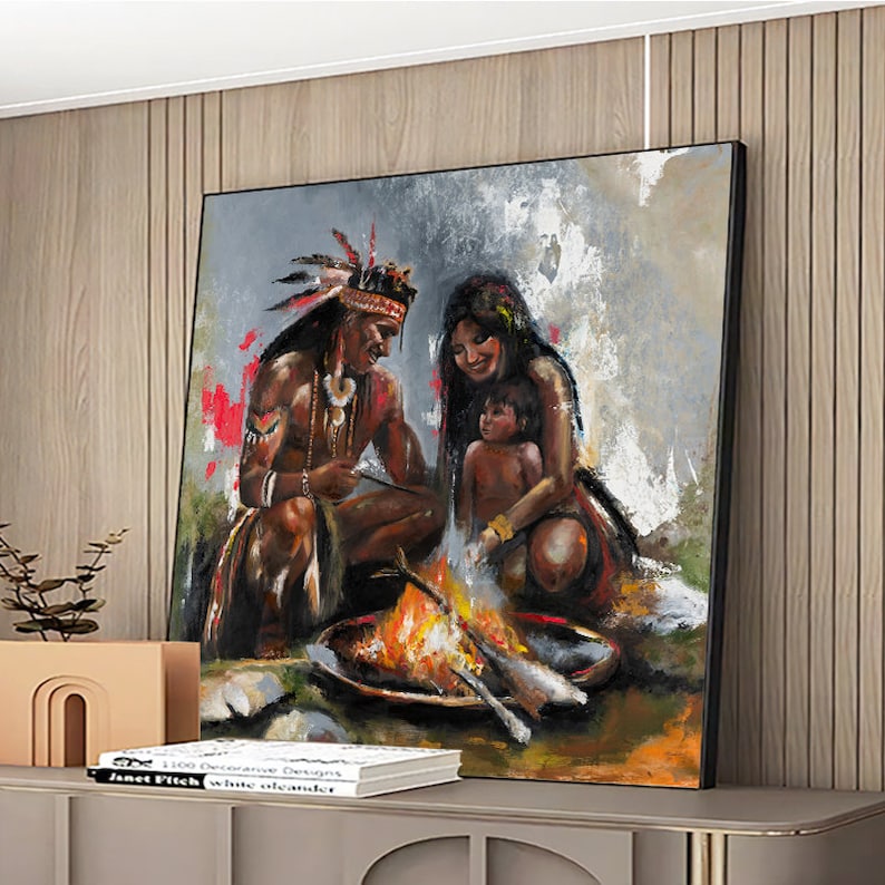 May include: A square oil painting depicting a family of three gathered around a campfire. The figures are rendered in warm earth tones with visible brushstrokes. The scene features a person in a feathered headdress, another adult, and a child.