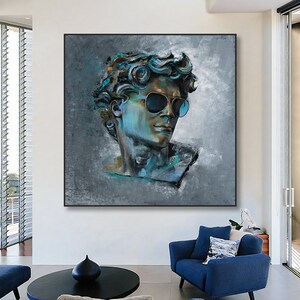 K&ouml;nnte beinhalten: Ein quadratisches Wandbild mit einem stilisierten, strukturierten &Ouml;lgem&auml;lde einer klassischen m&auml;nnlichen B&uuml;ste, die eine dunkle Sonnenbrille tr&auml;gt. Das Portr&auml;t ist in Blau-, Petrol- und Graut&ouml;nen auf einem gesprenkelten grauen Hintergrund gehalten.