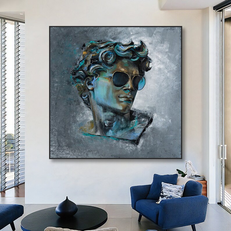 K&ouml;nnte beinhalten: Ein quadratisches Wandbild mit einem stilisierten, strukturierten &Ouml;lgem&auml;lde einer klassischen m&auml;nnlichen B&uuml;ste, die eine dunkle Sonnenbrille tr&auml;gt. Das Portr&auml;t ist in Blau-, Petrol- und Graut&ouml;nen auf einem gesprenkelten grauen Hintergrund gehalten.