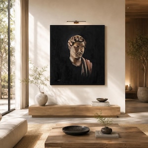May include: A square framed oil painting depicting a classical Roman-style bust of a person with curly hair and a draped garment, set against a dark, moody background. The artwork is mounted on a light-colored wall above a wooden console table.