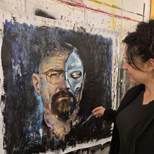 May include: A large square painting on canvas featuring a portrait of a man with a beard and glasses. The left side shows a realistic human face, while the right side depicts a metallic, robotic skull with a glowing yellow eye against a dark background.