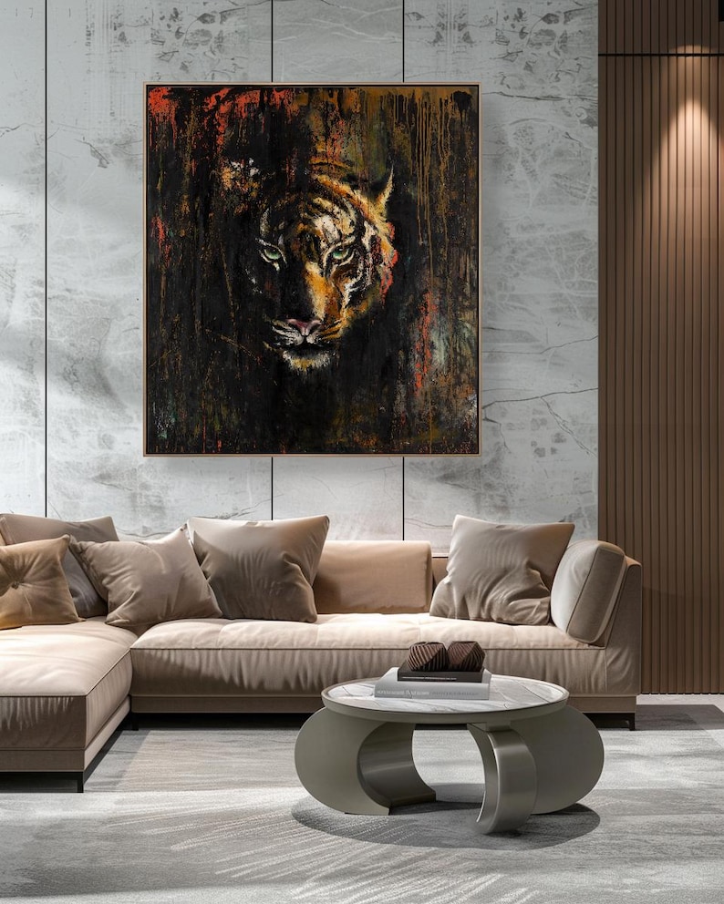 May include: A square wall art piece featuring a detailed tiger face emerging from a dark, textured background with streaks of black, brown, and vibrant orange paint. The artwork is enclosed in a thin, simple frame and mounted on a light wall.