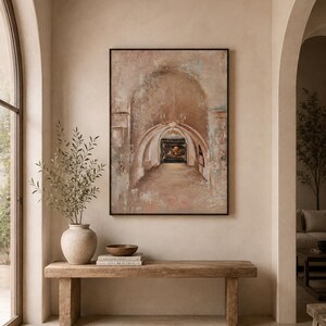 May include: A rectangular framed wall art piece depicting an arched stone hallway with a chandelier and a dark doorway. The artwork features muted beige, brown, and soft blue tones with a textured, weathered appearance in a black frame.