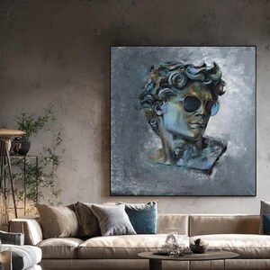 K&ouml;nnte beinhalten: Ein quadratisches Wandbild mit einem stilisierten, malerischen Portr&auml;t einer klassischen m&auml;nnlichen B&uuml;ste, die eine dunkle Sonnenbrille tr&auml;gt. Das Kunstwerk verwendet eine Palette aus k&uuml;hlen Blaut&ouml;nen, Graut&ouml;nen und tiefen Schatten.