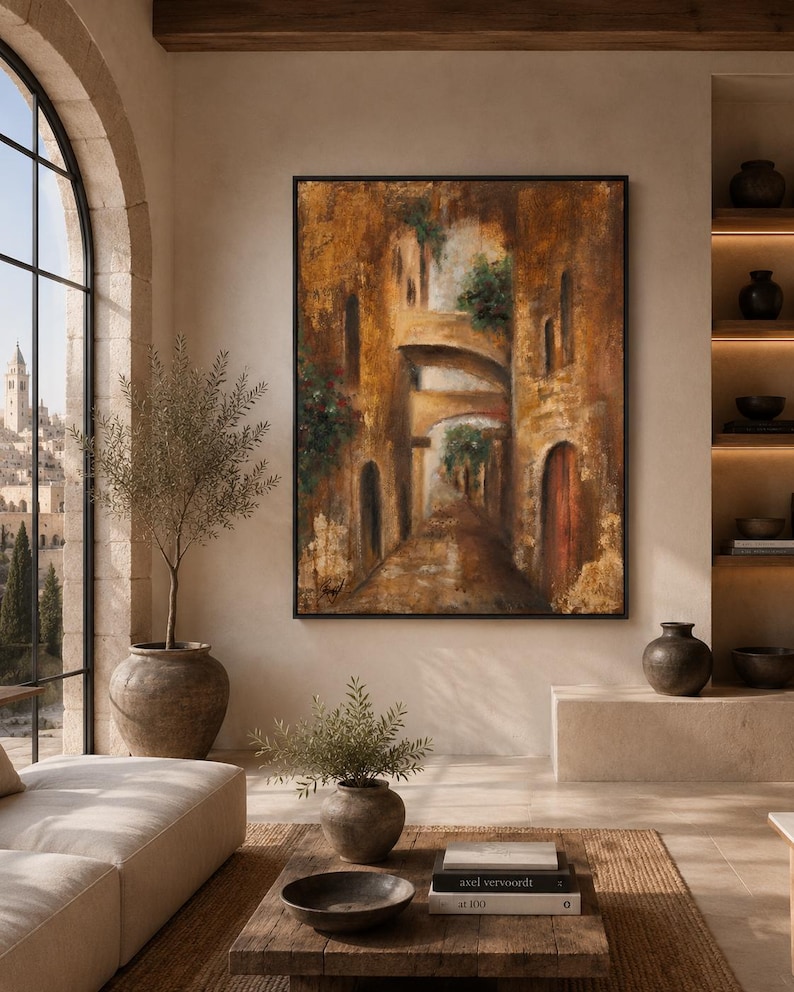 May include: A large rectangular framed oil painting depicting a narrow Mediterranean street scene with stone arches, textured golden-brown walls, and green foliage. The artwork features a dark wooden frame and is displayed on a neutral wall.