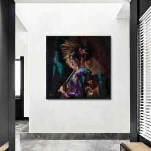Op de afbeelding: Een vierkante muurkunstprint met een schilderij van een persoon in een paars en blauw patroon kledingstuk die een grote, getextureerde goud- en bruinkleurige paraplu vasthoudt. De achtergrond is donker met abstracte spatten van groenblauwe en zwarte verfstreken.
