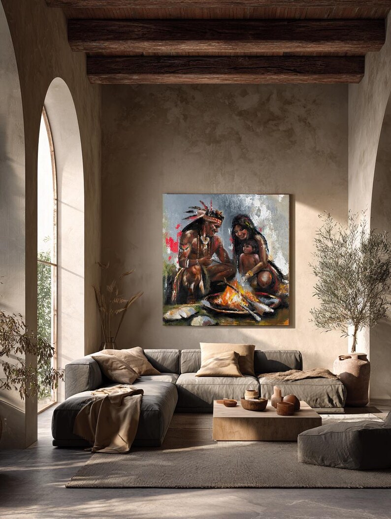 May include: A square wall art print featuring an oil painting of a family sitting around a campfire. The scene depicts a person with a feathered headdress, another person, and a small child, all rendered with textured brushstrokes and warm tones.