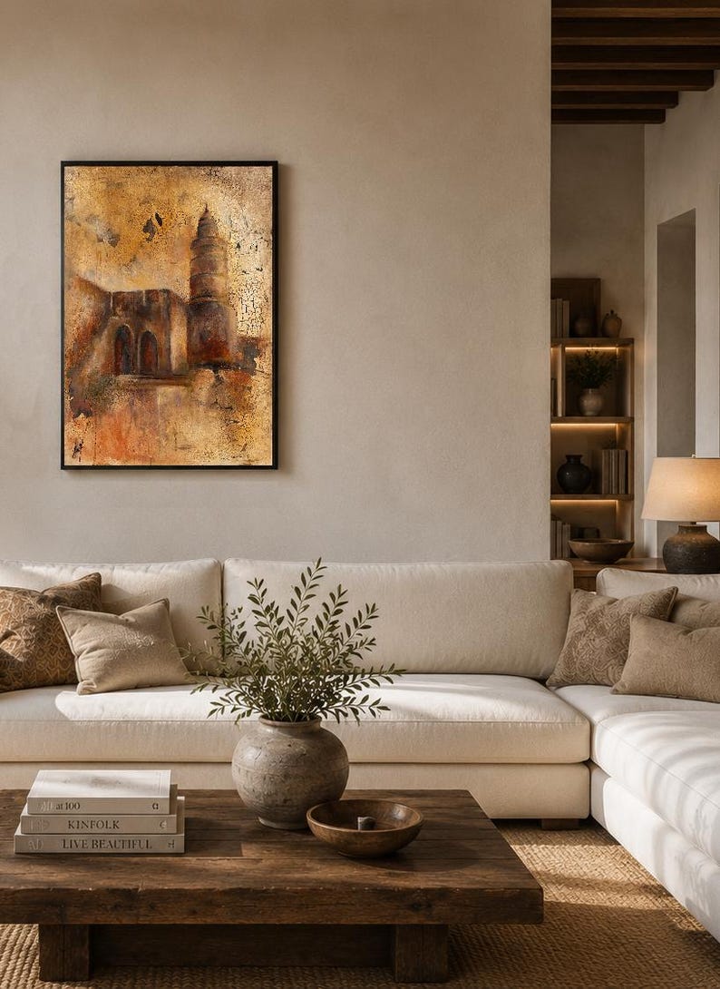 May include: A rectangular wall art piece in a black frame featuring an abstract, textured painting of a tall tower and building structure in shades of gold, brown, and deep orange, with a distressed, weathered finish across the entire surface.