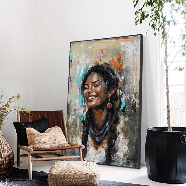 May include: A large rectangular framed oil painting featuring a portrait of a smiling person with dark braided hair. The artwork uses a textured palette of beige, gray, and black with vibrant splashes of orange and turquoise paint throughout.