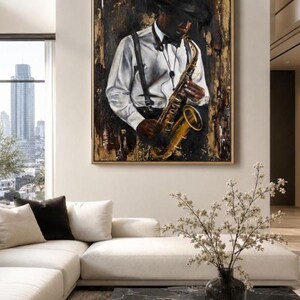 Op de afbeelding: Een ingelijst olieverfschilderij van een muzikant in een wit overhemd, zwarte bretels en een fedora-hoed, die een gouden saxofoon bespeelt. Het kunstwerk heeft een donkere, getextureerde achtergrond met gouden accenten.