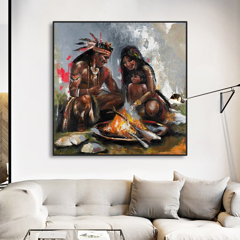 May include: An oil painting on canvas depicting a family of three gathered around a campfire. The figures are rendered in warm earth tones with visible brushstrokes. The scene features a person in a feathered headdress, another person, and a child.