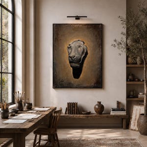 May include: A large rectangular wall art piece featuring a dark, sculptural lion head relief centered on a textured, golden-brown background. The artwork is framed in black and illuminated by a slim, horizontal black light fixture mounted above it.