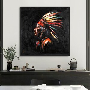 May include: A square wall art piece featuring a profile portrait of a person wearing a traditional feathered headdress. The artwork uses a dark black background with vibrant, textured brushstrokes in red, yellow, and white on the feathers.