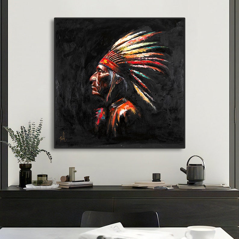 May include: A square wall art piece featuring a profile portrait of a person wearing a traditional feathered headdress. The artwork uses a dark black background with vibrant, textured brushstrokes in red, yellow, and white on the feathers.