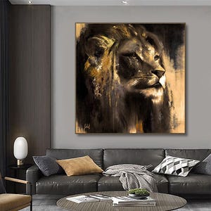Op de afbeelding: Een vierkante wandkunstprint met een gedetailleerd schilderij van een leeuwenkop in profiel. Het kunstwerk gebruikt een donker kleurenpalet met diepzwarte schaduwen en accenten van goud- en bruintinten, met een handtekening zichtbaar in de hoek.