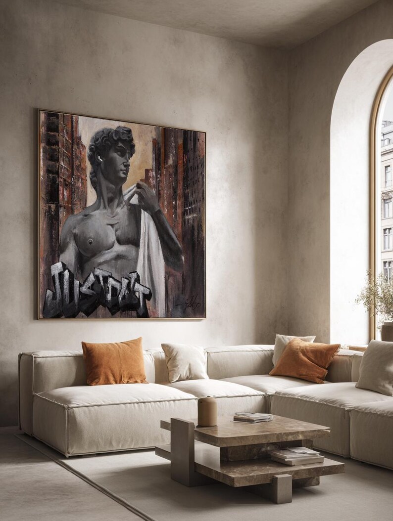 May include: A square canvas wall art piece featuring a greyscale depiction of a classical statue bust wearing a white earbud. The background shows a dark, abstract urban cityscape. The word JUSTDOIT is written in bold, black graffiti-style lettering.