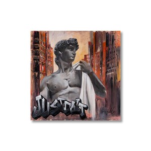 May include: A square canvas painting featuring a grey bust of David wearing a white earbud, draped in a white cloth. The background shows orange and brown city buildings. The word JUST DO IT is written in large, grey, 3D-style graffiti lettering.
