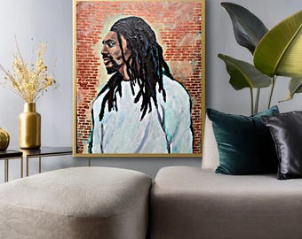 May include: A framed portrait of a person with long black dreadlocks, wearing a white shirt, set against a brick wall background. The artwork is displayed in a gold frame, adding a touch of elegance to the piece. The painting is a portrait.