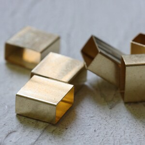 May include: A group of five gold-colored metal squares, some stacked on top of each other. The squares are all different sizes and shapes.