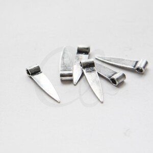 May include: A group of six silver-toned metal pendant charms shaped like a pointed leaf with a loop at the top.