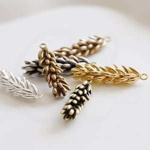 May include: Four gold-toned pine cone charms with a loop for hanging. The charms are in different sizes and have a textured surface.