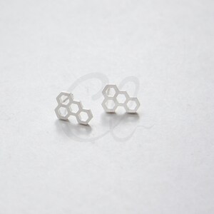May include: A pair of silver honeycomb-shaped stud earrings.