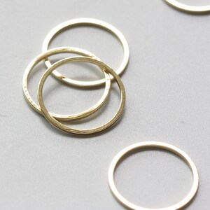 May include: Three gold-coloured metal rings, stacked on top of each other. The rings are smooth and have a slightly textured surface.