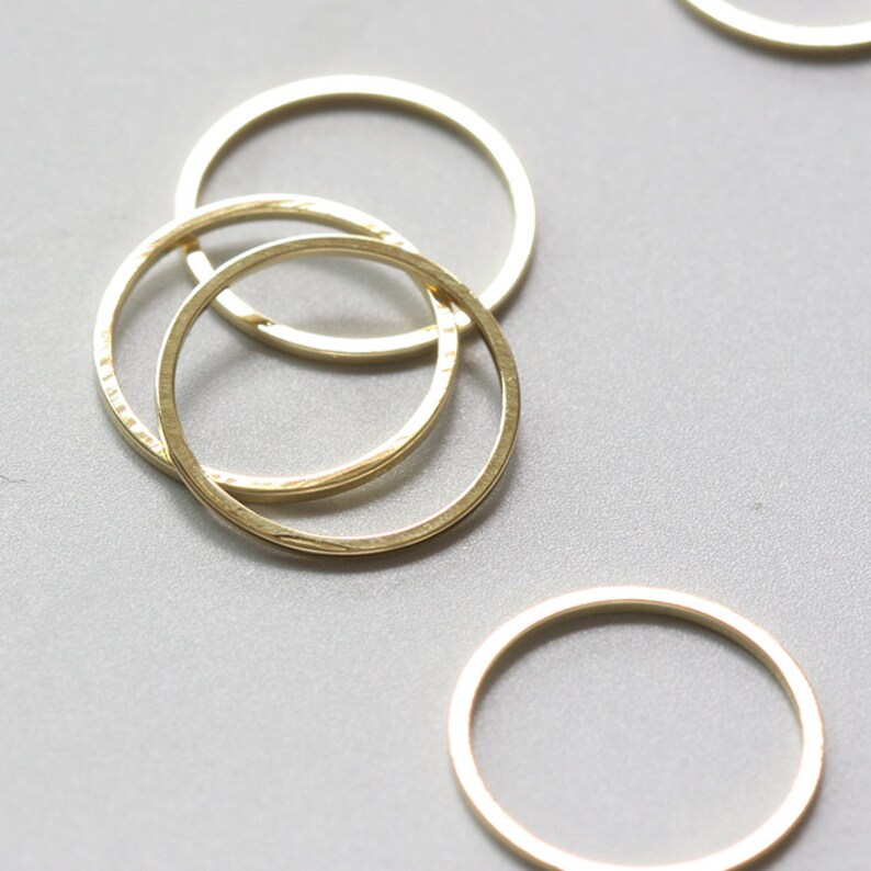 May include: Three gold-coloured metal rings, stacked on top of each other. The rings are smooth and have a slightly textured surface.