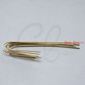 Puede incluir: Primer plano de un paquete de diez bucles de alambre de latón crudo de color dorado. El alambre es delgado y tiene un acabado liso y brillante.