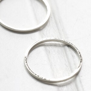 May include: Two silver hoop earrings, one is smooth and the other has a textured edge.
