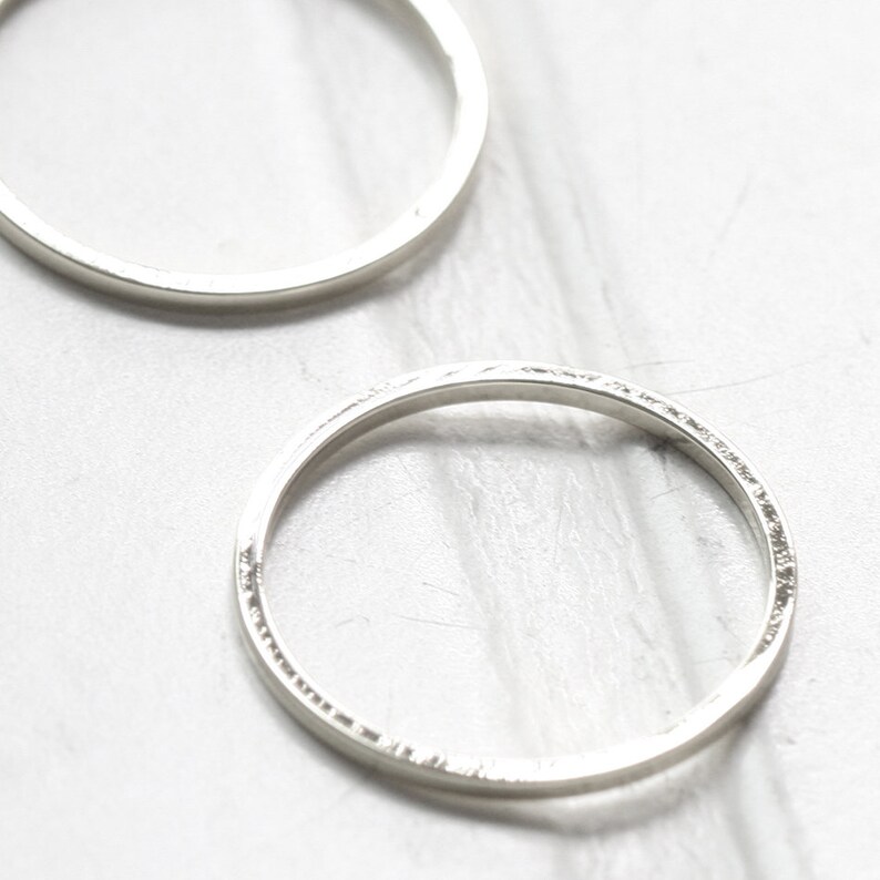 May include: Two silver hoop earrings, one is smooth and the other has a textured edge.