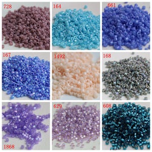 Peut inclure: Une collection de petites perles de rocaille colorées de différentes nuances. L'image présente neuf tas de perles séparés, notamment des nuances de violet, de bleu, de pêche et de sarcelle. Chaque tas est étiqueté avec un numéro, probablement pour l'identification des couleurs. Ces perles conviennent à la fabrication de bijoux et à l'artisanat.
