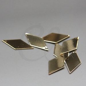 Könnte beinhalten: Eine Gruppe von sechs goldfarbenen, rautenförmigen Metallanhängern mit einem Loch oben.