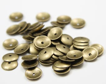 May include: A pile of antique gold-toned metal beads. The beads are round and have a raised centre. They are perfect for jewellery making or other craft projects.