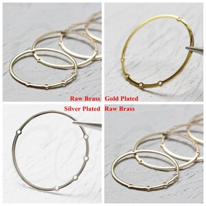 May include: Four metal rings in different finishes: raw brass, gold plated, silver plated, and raw brass. The rings are circular and have six evenly spaced holes around the circumference.