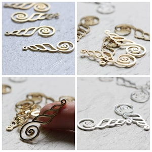 Puede incluir: Una colección de abalorios de metal dorado y plateado con forma de conchas estilizadas con intrincados diseños de espiral.