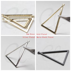 Puede incluir: Cuatro blanks de pendientes de metal en forma de triángulo en diferentes acabados: latón en bruto, chapado en oro, chapado en plata y negro mate.