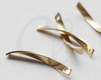 Könnte beinhalten: Drei goldfarbene Metallstücke mit einer gebogenen Form und einem kleinen Loch an einem Ende. Die Stücke sind in einem Kreuzmuster auf einer weißen Oberfläche angeordnet. Rohmessing.